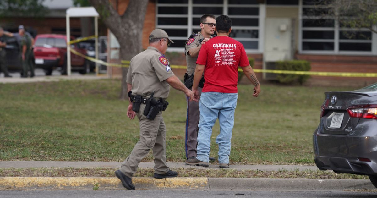 Law enforcement officers speak to a man outside of Robb Elementary School in Uvalde, Texas, on May 24, the day a gunman killed 19 children and two adults before being killed by Border Patrol agents.