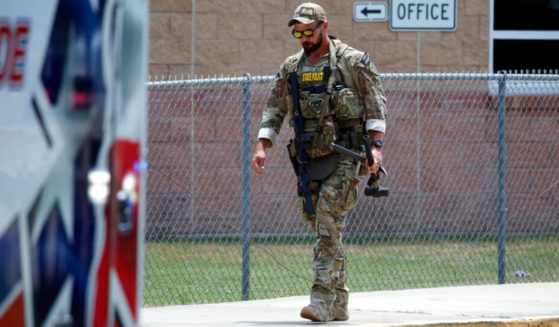A Texas State Police officer walks outside Robb Elementary School following the mass shooting May 24 in Uvalde, Texas. A new report indicates two police officers had a chance to shoot the gunman before he entered the school, but they hesitated because they were afraid of hitting children who were playing nearby.