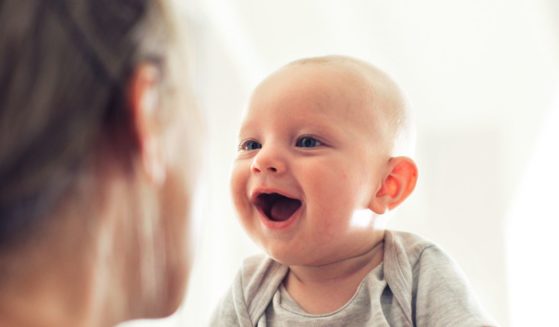 A baby smiles in this stock image.