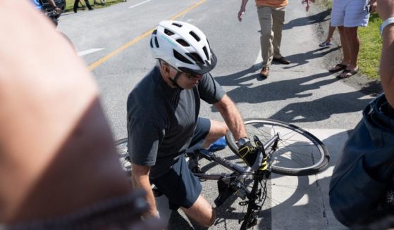 President Joe Biden falls off his bicycle as he approaches a crowd at a state park in Rehoboth Beach, Delaware, on Saturday.