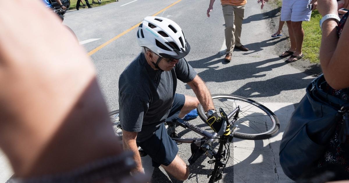 President Joe Biden falls off his bicycle as he approaches a crowd at a state park in Rehoboth Beach, Delaware, on Saturday.