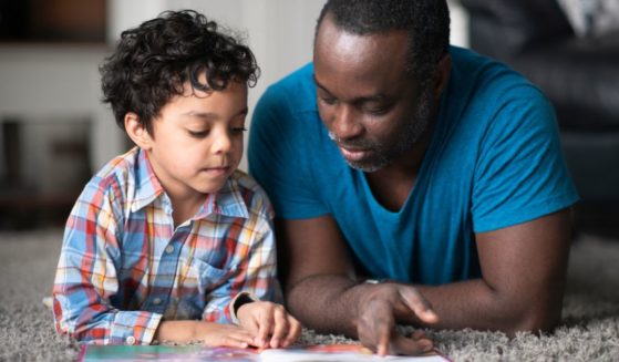 A father reads to his son in the above stock image.