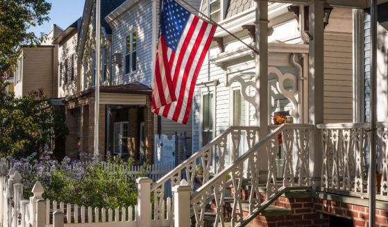 An American flag flies outside of a house in this stock image.