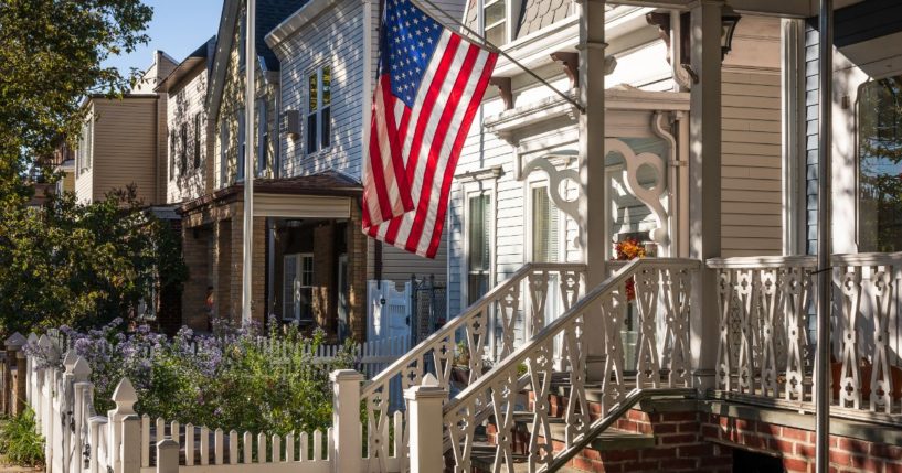 An American flag flies outside of a house in this stock image.