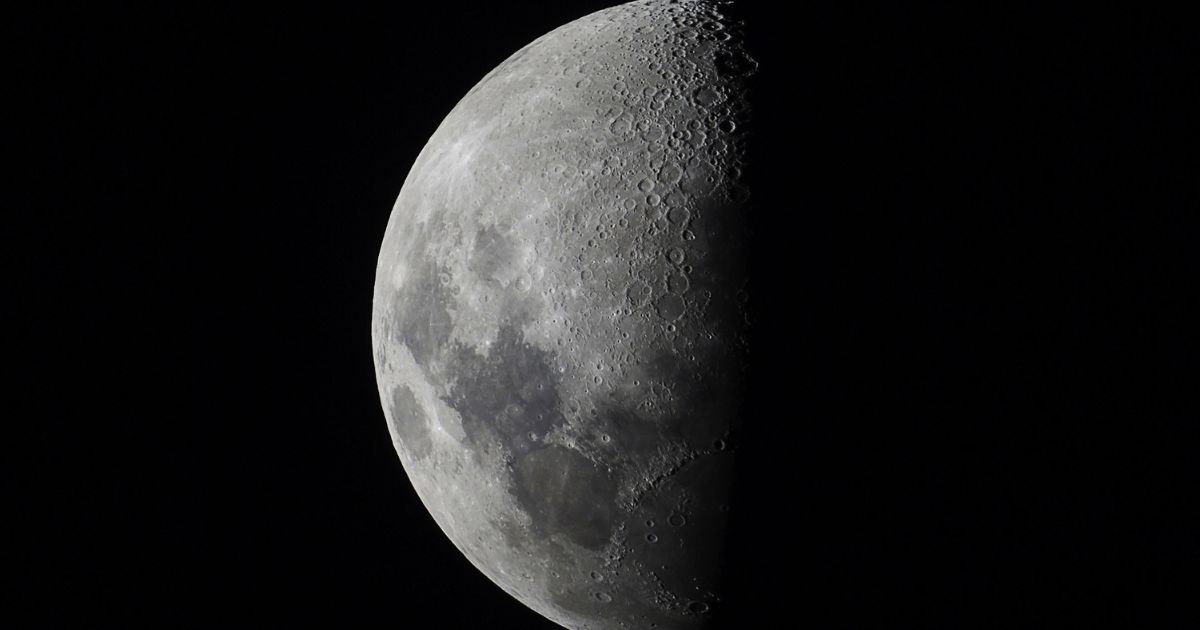 Many craters are visible on the quarter-phase moon.