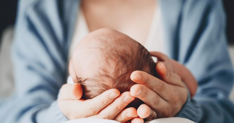 A mother holds her baby in this stock image.