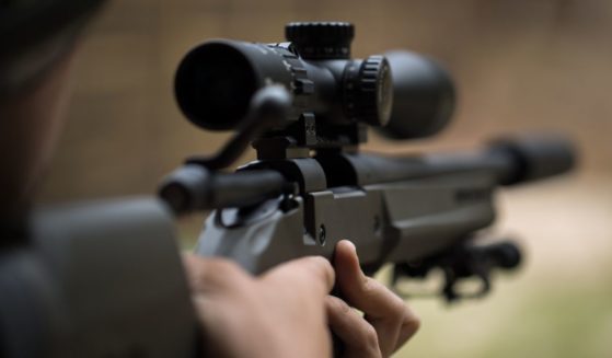 A man shoots a rifle in this stock image.