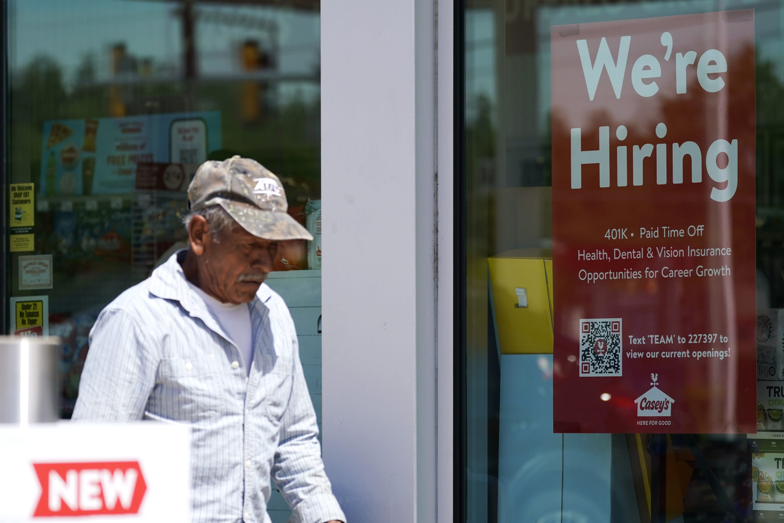 A customer walks past a hiring sign at a gas station in Buffalo Grove, Ill., June 9. More Americans applied for unemployment benefits last week, the fifth consecutive week that claims topped the 230,000 mark, the Labor Department reported.