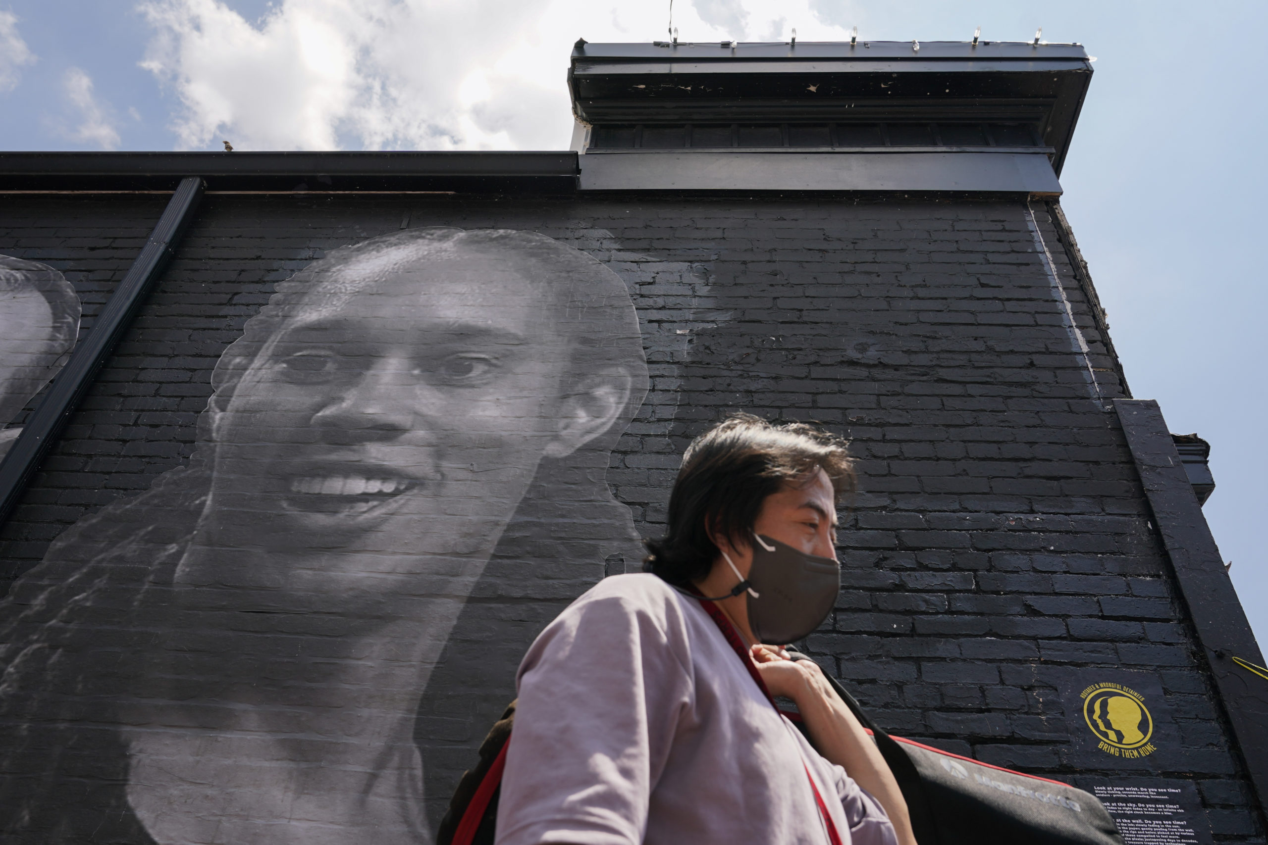 A visitor in the Georgetown neighborhood of Washington walks down an alley past a mural depicting WNBA star Brittney Griner and other American hostages and wrongful detainees who are being held abroad.