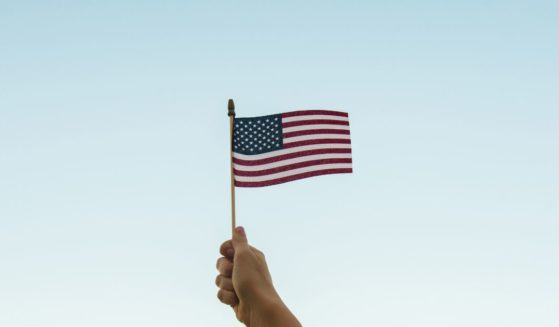 A person holds an American flag in the above stock image.