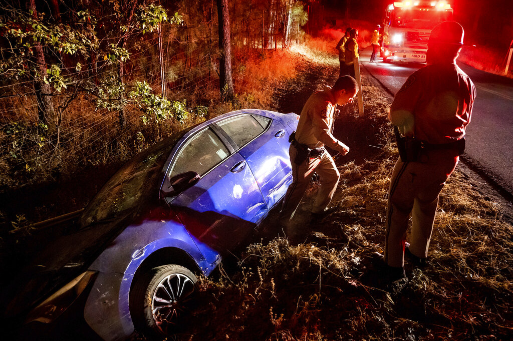a California Highway Patrol officer walking away from a car that crashed into a ditch