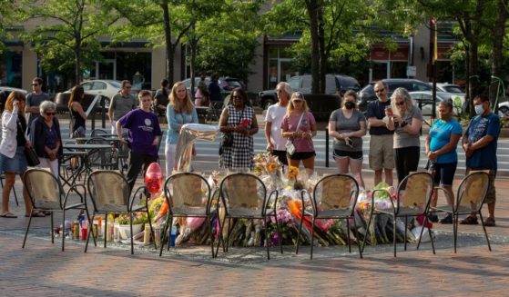 A dozen people pay tribute to the victims of the July 4 parade shooting in Highland Park, Illinois, by standing around a make-shift memorial in the city's center on July 10.