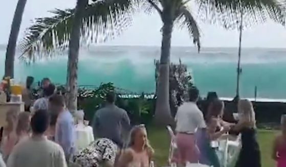 Wedding guests watch as a large wave approaches their outdoor celebration in Kailua-Kona, Hawaii.