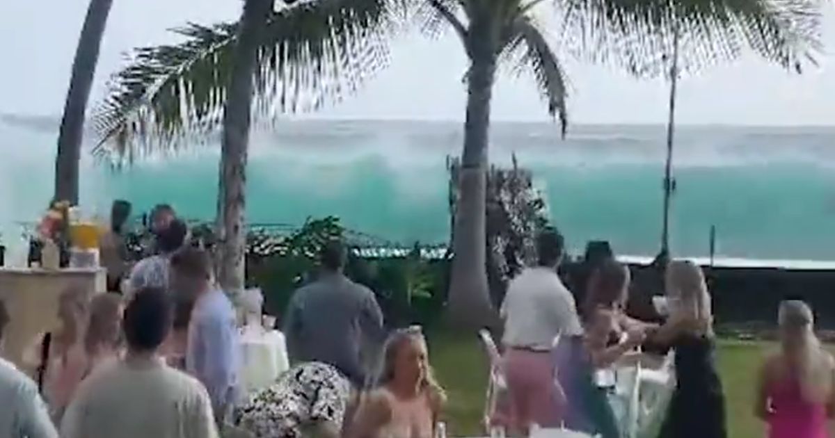 Wedding guests watch as a large wave approaches their outdoor celebration in Kailua-Kona, Hawaii.