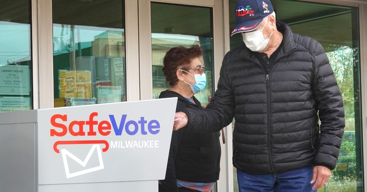 Wisconsin residents drop ballots into an official ballot box outside of the Tippecanoe branch library in Milwaukee on Oct. 20, 2020.