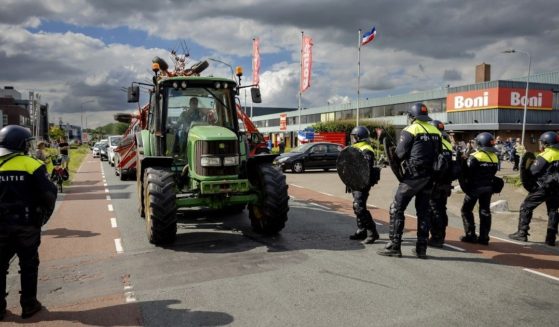 Farmers remove tractors forming a blockade at the police's request at a distribution center of supermarket chain Boni during a demonstration against the Dutch government's plans to cut nitrogen emissions on Tuesday.