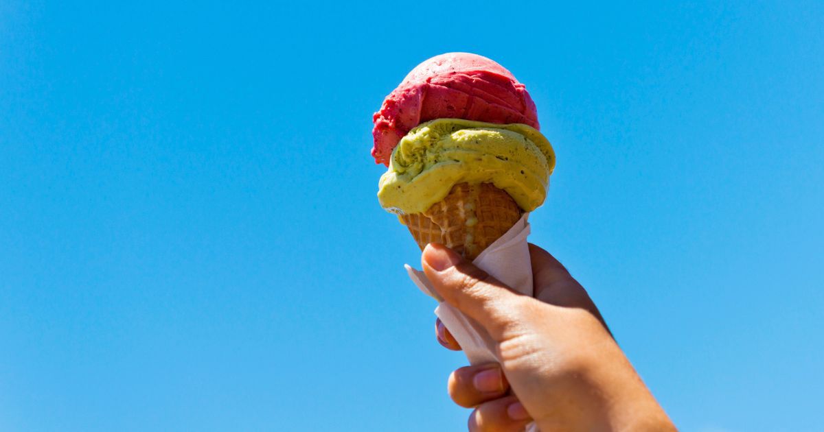 A person holds an ice cream cone on a summer day.