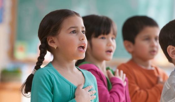 Children say the Pledge of Allegiance in the above stock image.