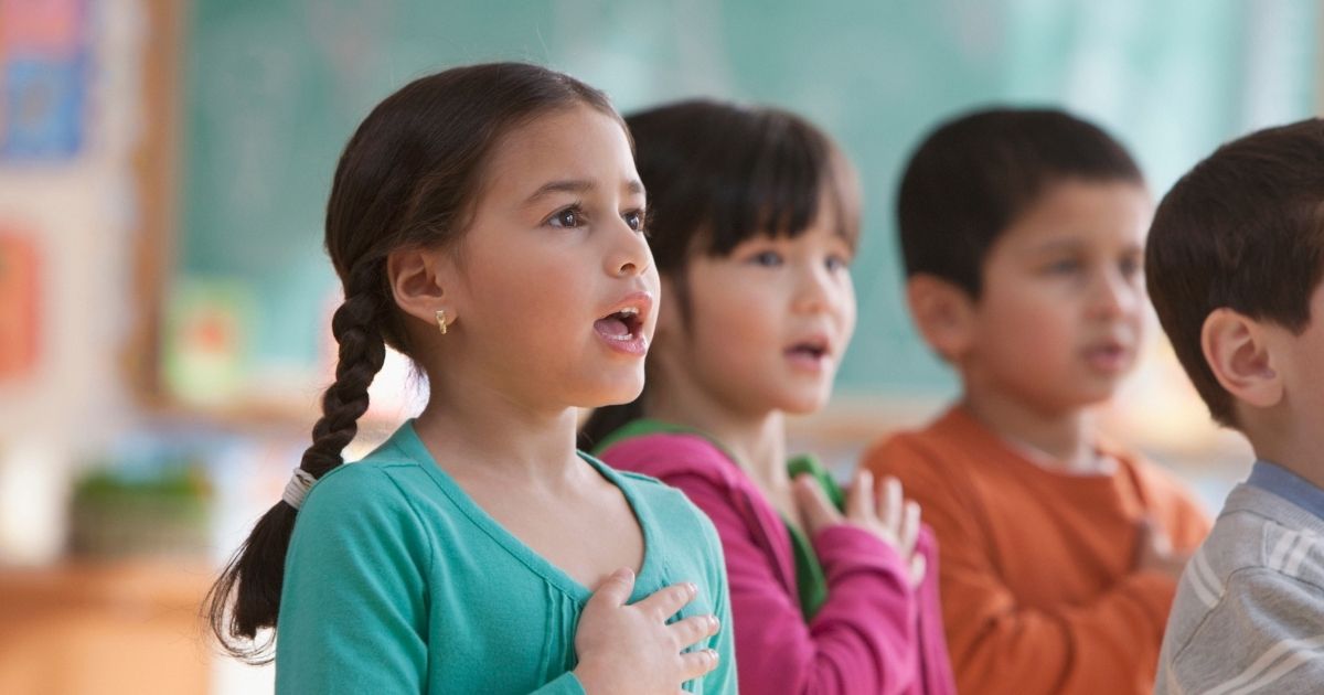 Children say the Pledge of Allegiance in the above stock image.
