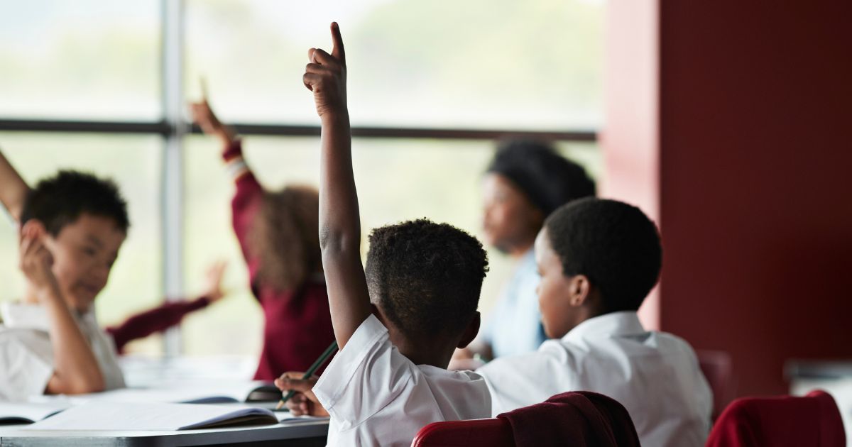 A student raises his hand in class in this stock image.