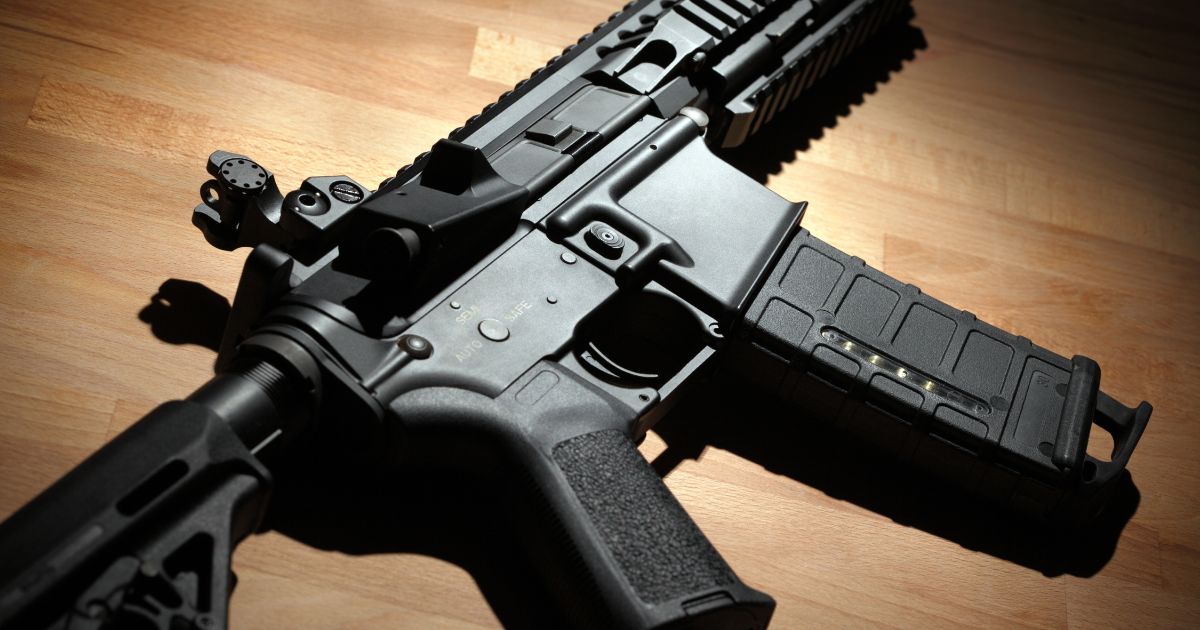 An AR-15 carbine is pictured on a wooden surface.