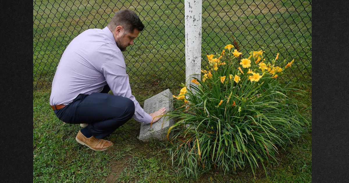 Brett Eagleson, son of 9/11 victim Bruce Eagleson, wipes grass off a memorial stone for his father at the baseball field where his father used to coach in a file photo from July 2021. Eagleson is part of a group of 9/11 survivors hoping to be awarded a portion of funds seized from the Afghan central bank.