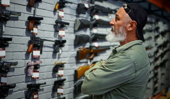 A man looks over the handgun selection at a gun store.