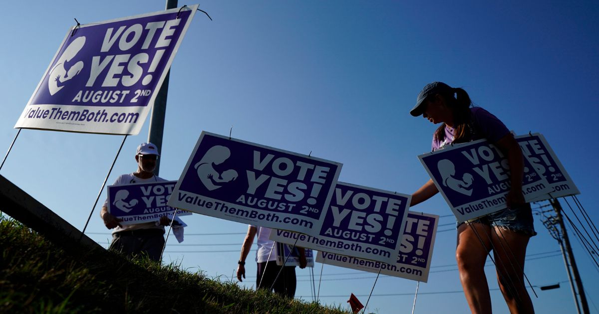 Supporters of a constitutional amendment on abortion remove signs on Aug. 1 in Olathe, Kansas.