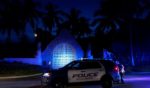 On the evening of Aug. 8, police stand outside the entrance to former President Donald Trump's Mar-a-Lago estate after an FBI raid of the residence that lasted the majority of the day.