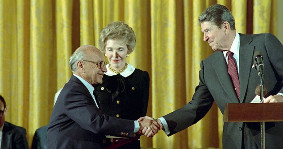 Milton Friedman shakes hands with President Ronald Reagan in the East Room of the White House on Oct. 17, 1988.