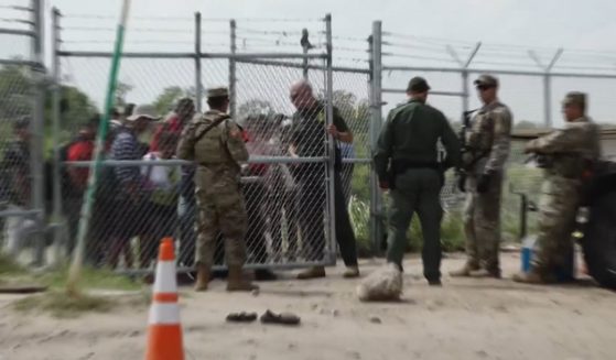 A Border Patrol agent opens a gate to allow illegal immigrants into Eagle Pass, Texas.