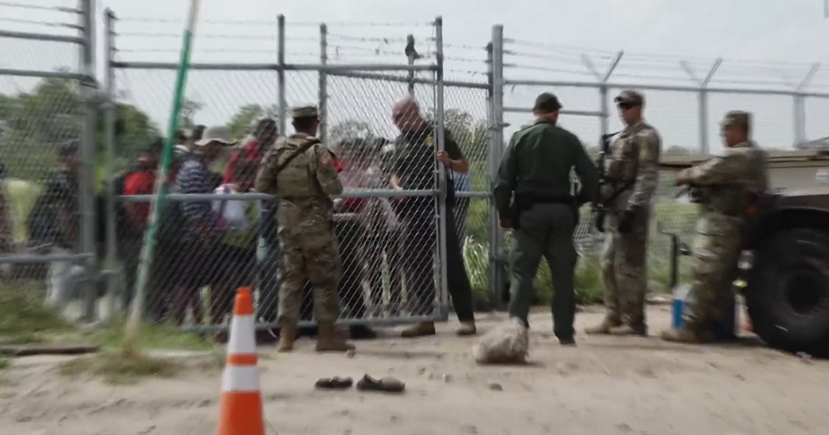 A Border Patrol agent opens a gate to allow illegal immigrants into Eagle Pass, Texas.