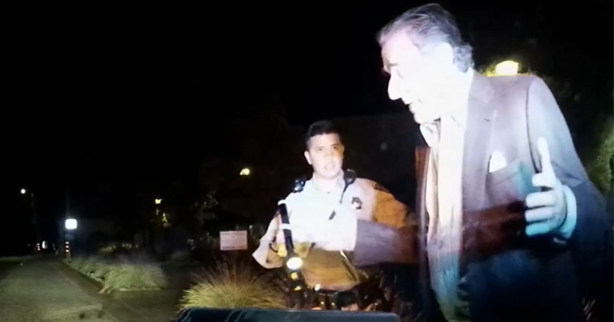 A police officer talks with Paul Pelosi before his drunken driving arrest.