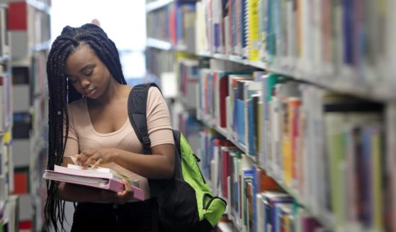 This stock photo shows a female student looking at a book in a library.