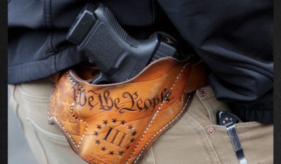 An attendee at a gun rights rally openly carries his gun in a holster stamped with "We the People" from the preamble to the United States Constitution in a file photo from January 2019.