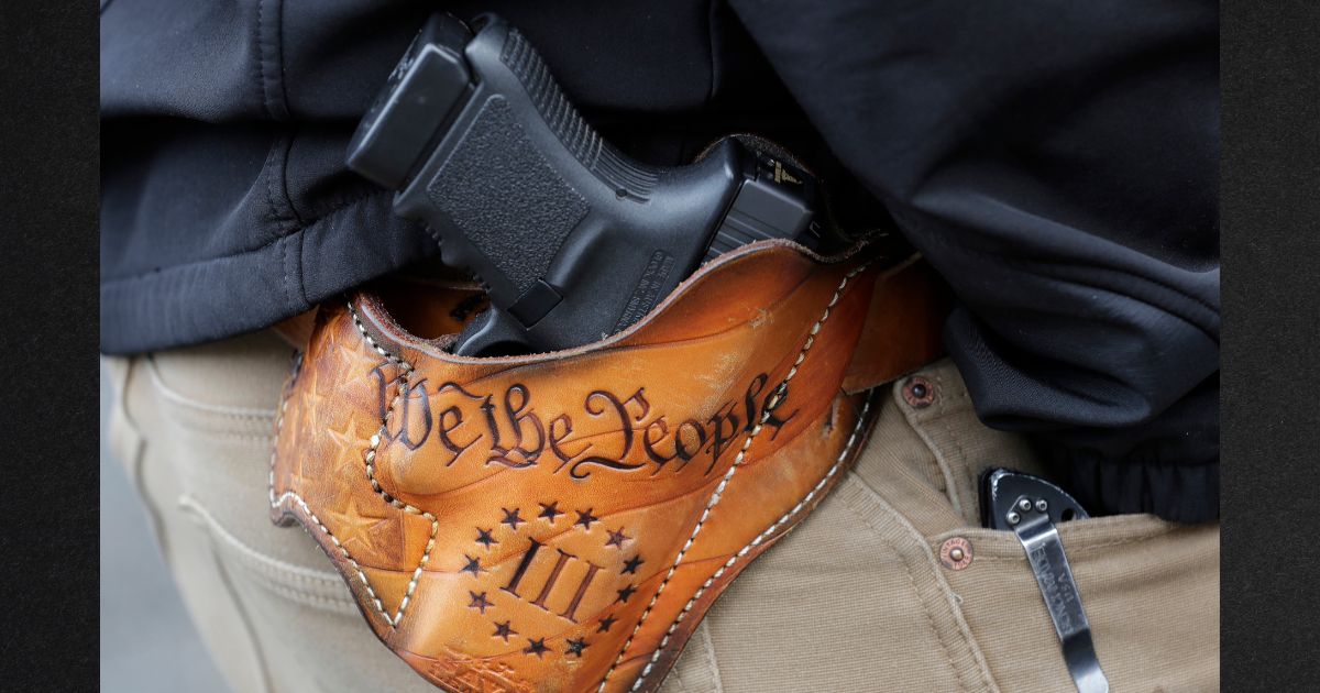 An attendee at a gun rights rally openly carries his gun in a holster stamped with "We the People" from the preamble to the United States Constitution in a file photo from January 2019.