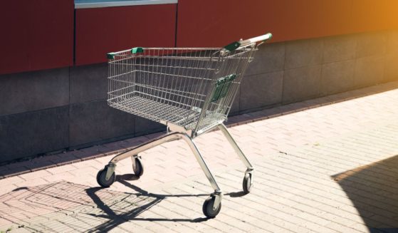 A shopping cart for groceries and other goods is parked near a store.