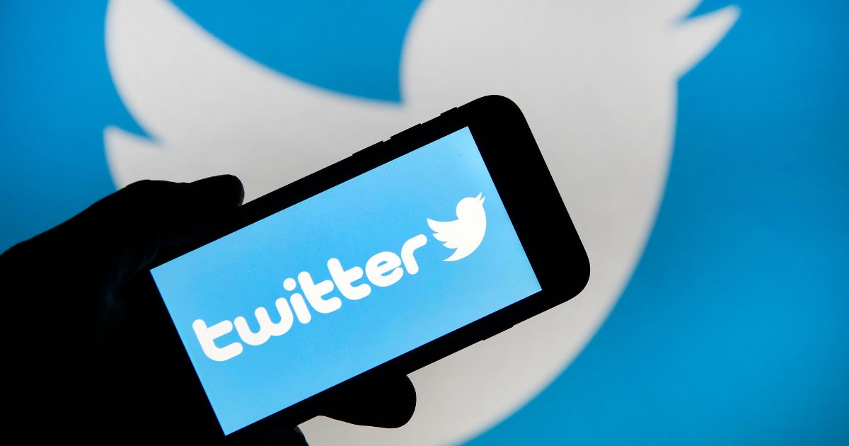 The Twitter logo is displayed on an iPhone in front of a computer screen, also displaying the logo, in Paris, France, on Feb. 7, 2019.
