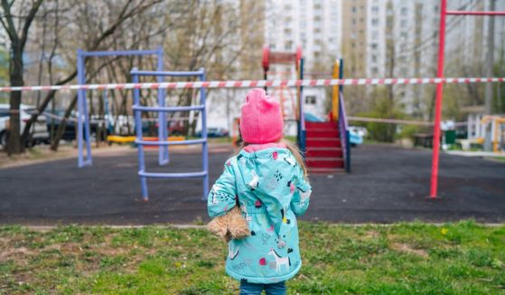 A child is seen from the back gazing at an empty playground.