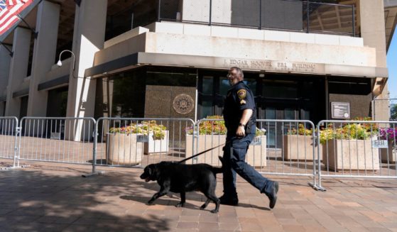 An officer with the FBI police patrols with a police dog outside the bureau's headquarters in Washington's J. Edgar Hoover Building in an Aug. 13 file photo.