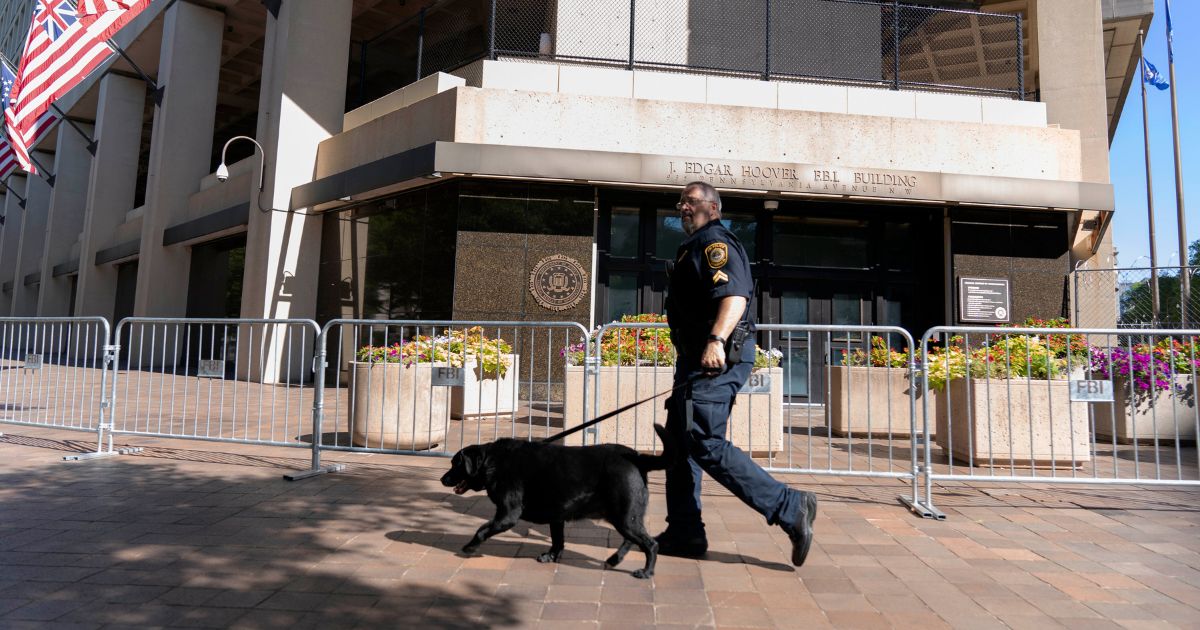 An officer with the FBI police patrols with a police dog outside the bureau's headquarters in Washington's J. Edgar Hoover Building in an Aug. 13 file photo.