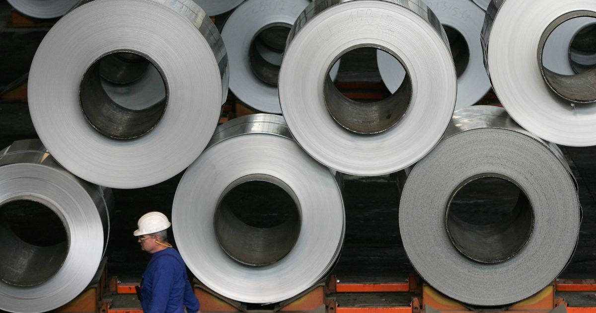 A worker walks among rolls of semi-finished aluminum at the Alcoa aluminum factory Oct. 24, 2006. in Szekesefehervar, Hungary.