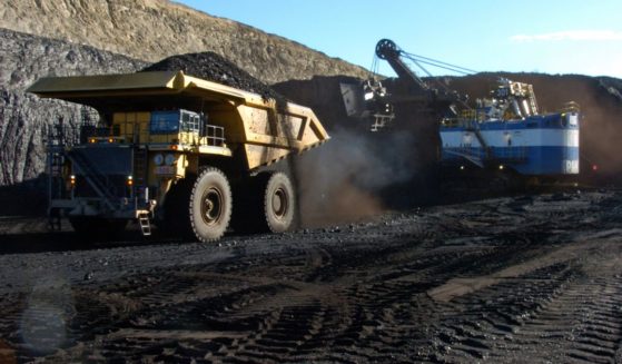 A yellow haul truck with a 250-ton capacity carrying a load of coal
