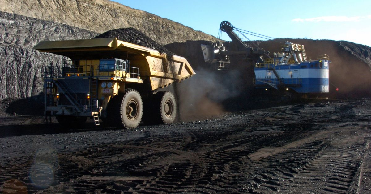 A yellow haul truck with a 250-ton capacity carrying a load of coal
