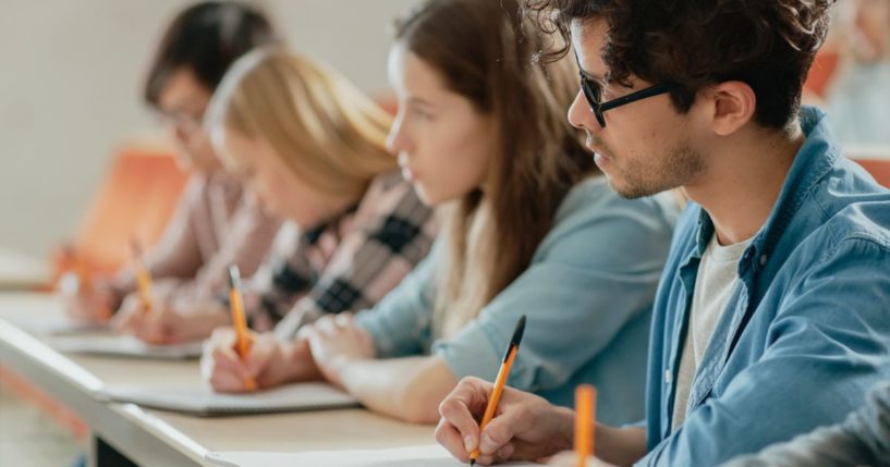 College students take notes during class in this stock image.