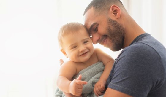 A father holds his baby in the above stock image.