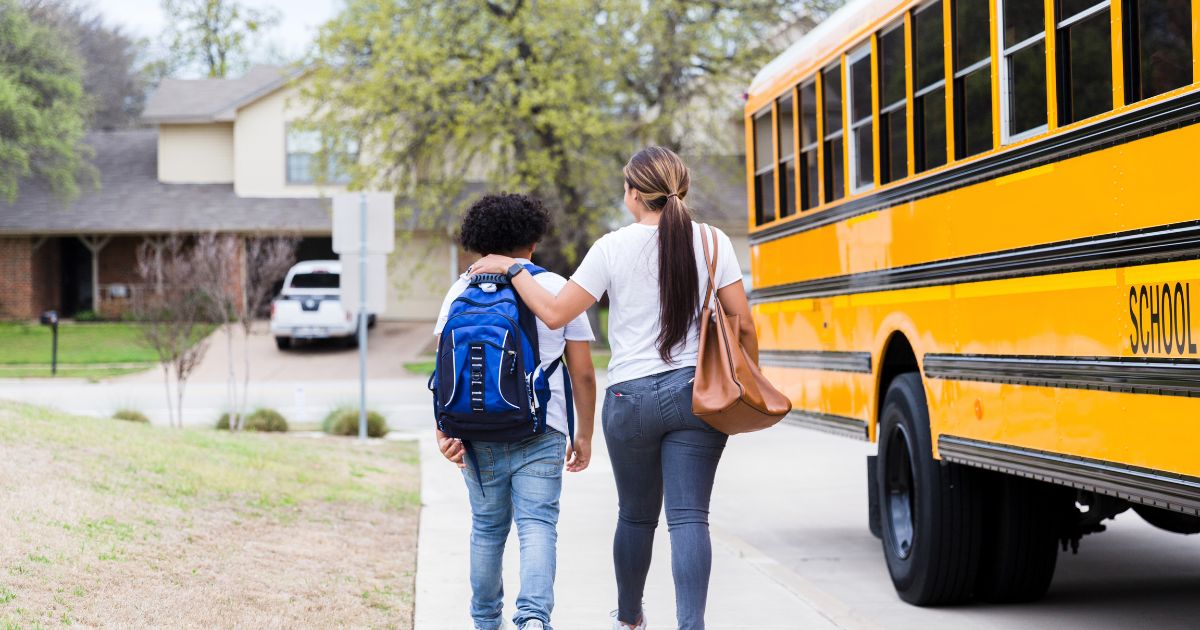 A mother and her son walk away from a school bus in this stock image.
