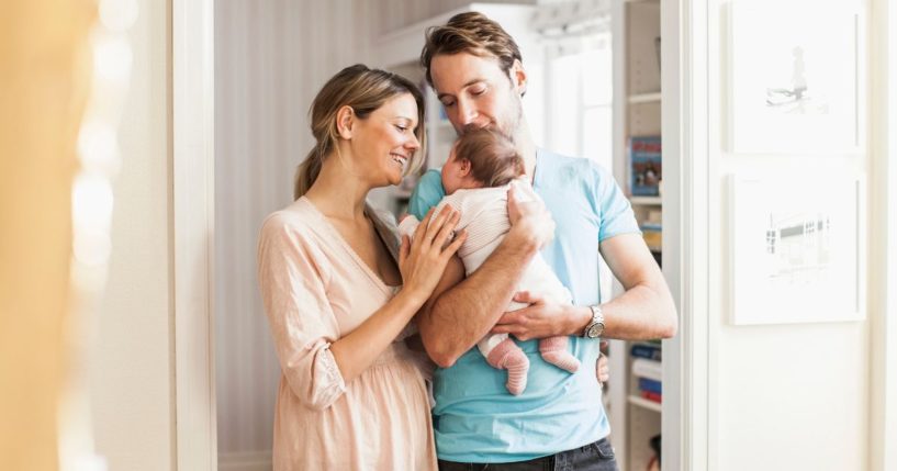 A mother and father hold their baby in this stock image.