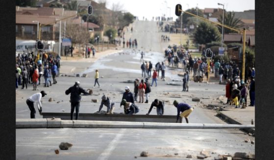 Protesters build a barricade to block a road after a night of riots caused by angry community members demanding better service delivery in Tembisa on Monday.