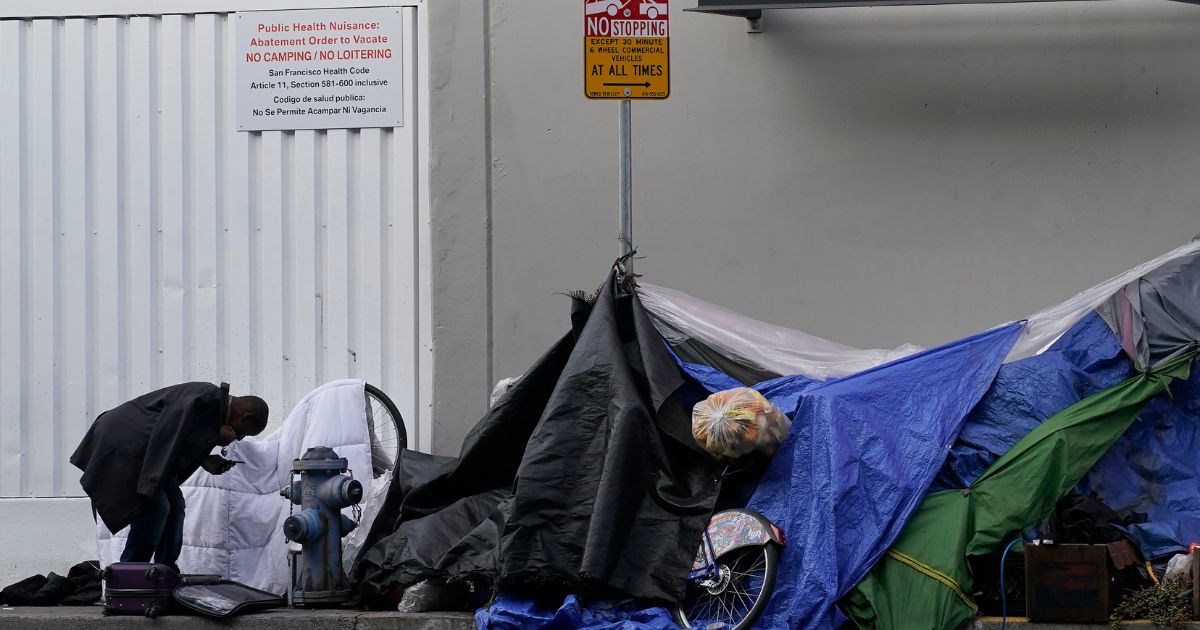 a man standing near tents set up on a sidewalk in San Francisco